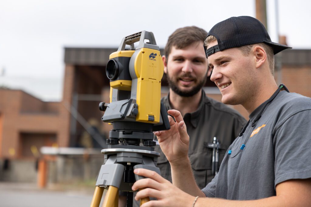 A student with a professor using land survey equipment